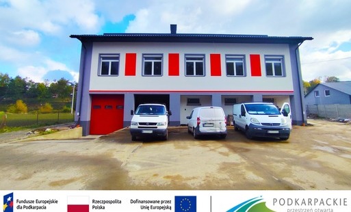 obraz dekoracyjny przedstawiający remizę w Manasterzu przed którą stoją 3 samochody 